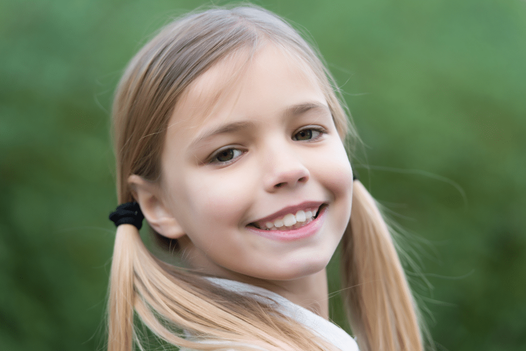 Smiling young girl with pigtails outdoors